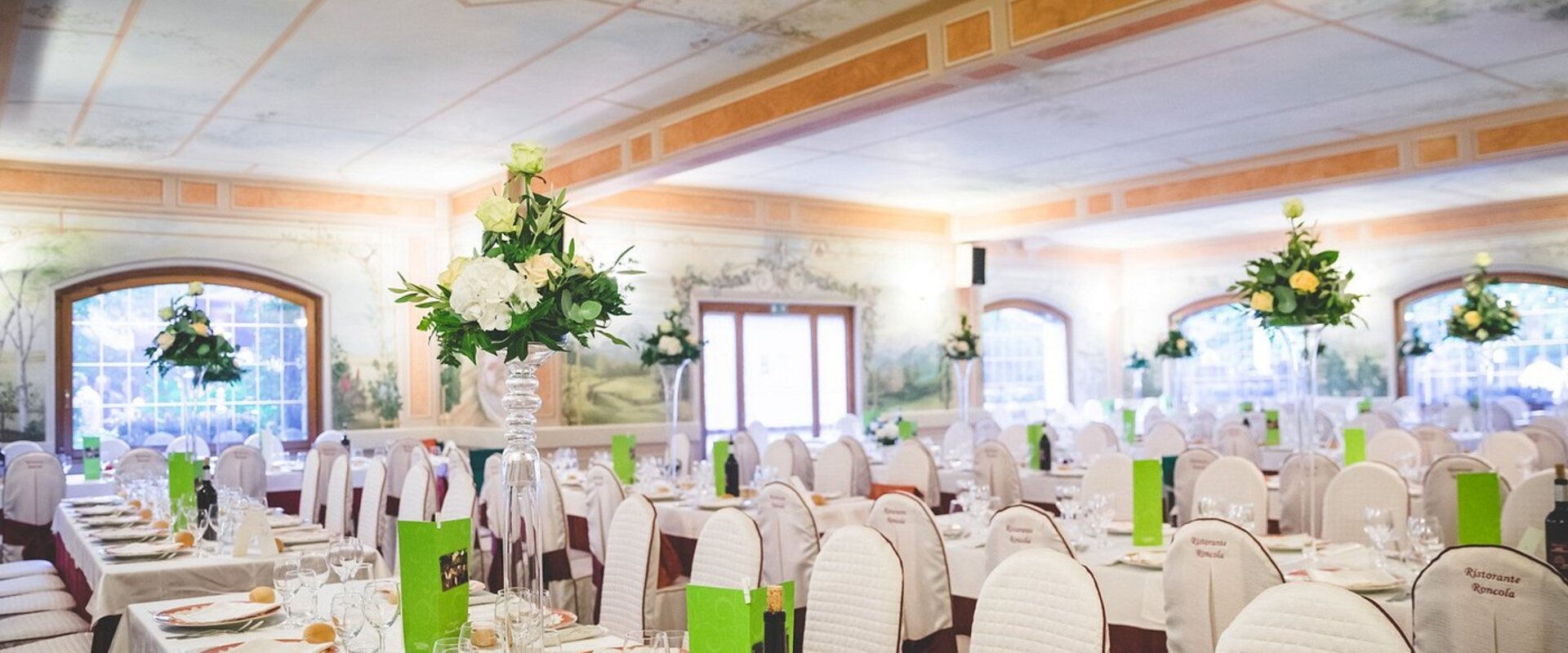 Ristorante Roncola, sala interna con tavoli apparecchiati e vista sulla collina